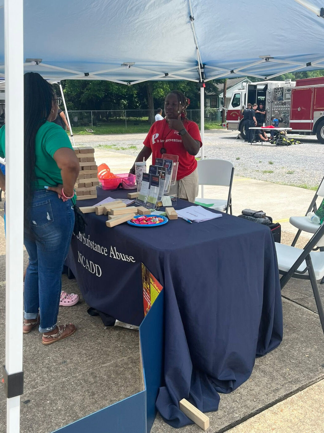 Prevention resource table under a blue canopy with a giant block-stacking game and brochures