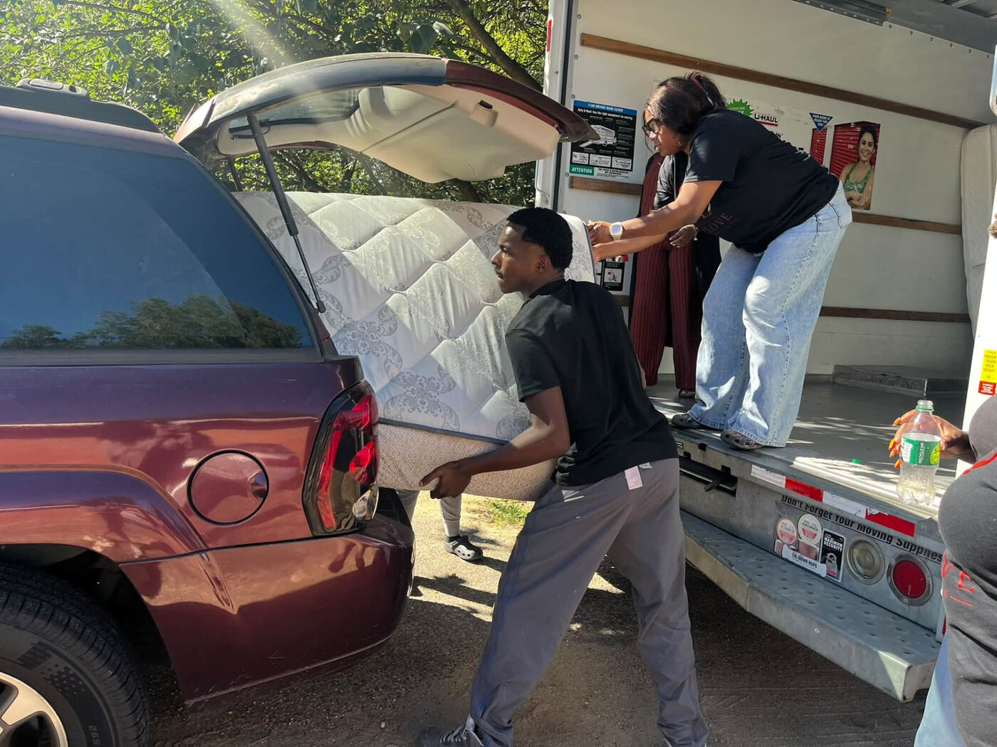 Volunteers loading a mattress into a family's vehicle