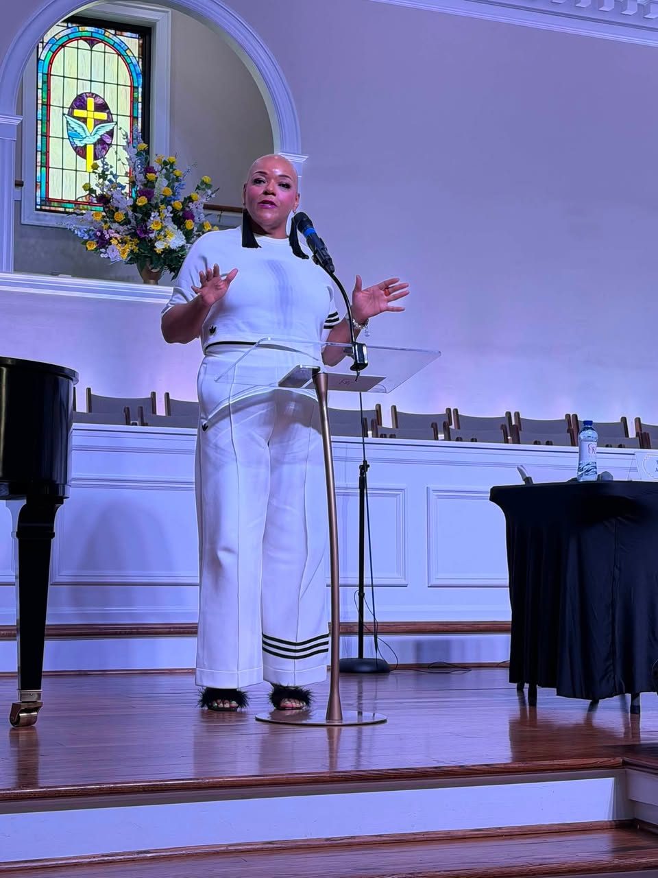 A speaker addressing the audience from a clear acrylic lectern on stage