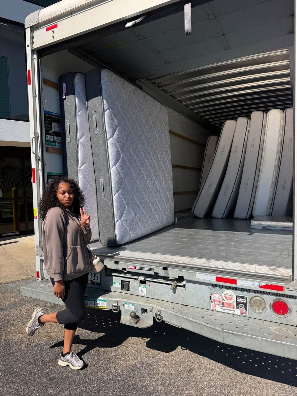 Volunteer standing beside a moving truck loaded with mattresses