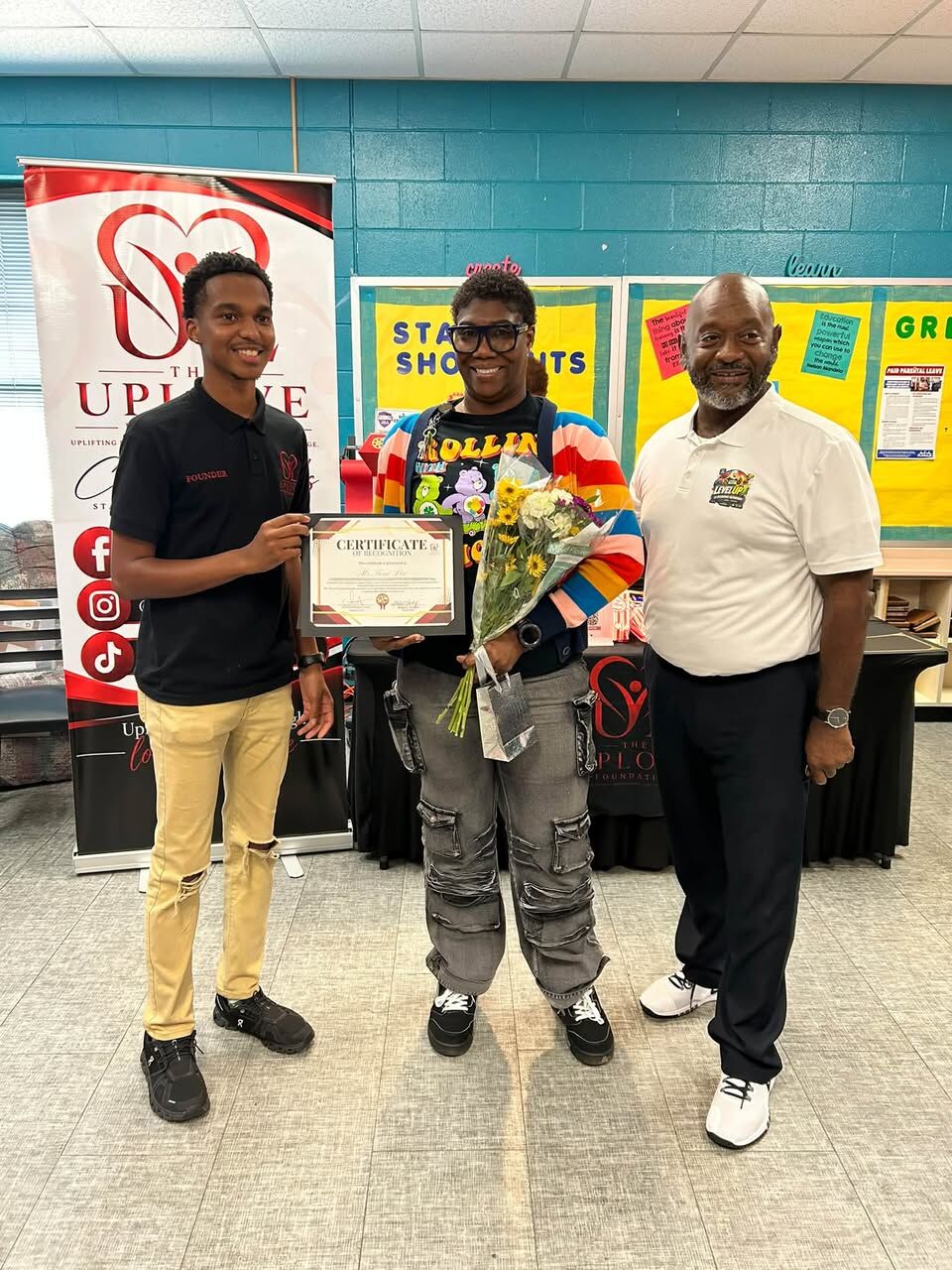 Isaiah presenting a certificate of recognition and flowers to a Fitzpatrick Elementary teacher