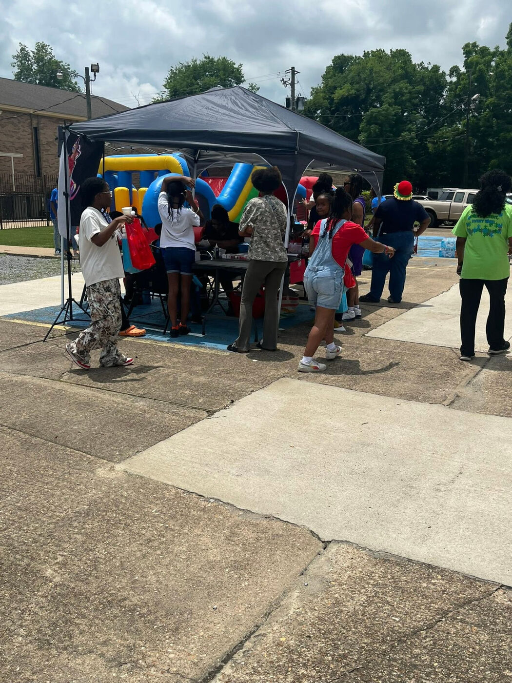Children and families gathered at a pop-up activity tent with a bounce house behind them