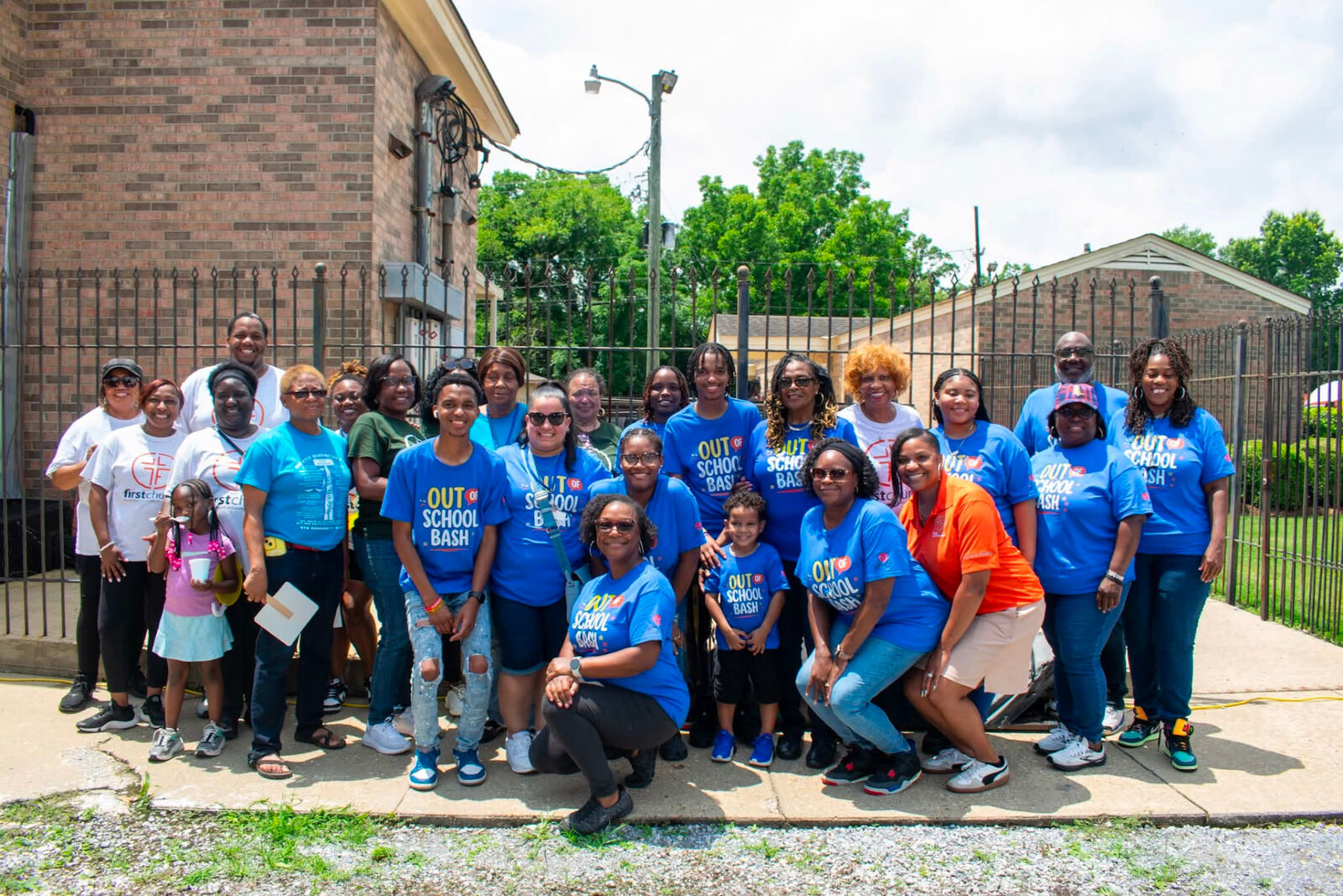 UpLove Foundation volunteers and community members in matching blue Out of School Bash shirts posing together
